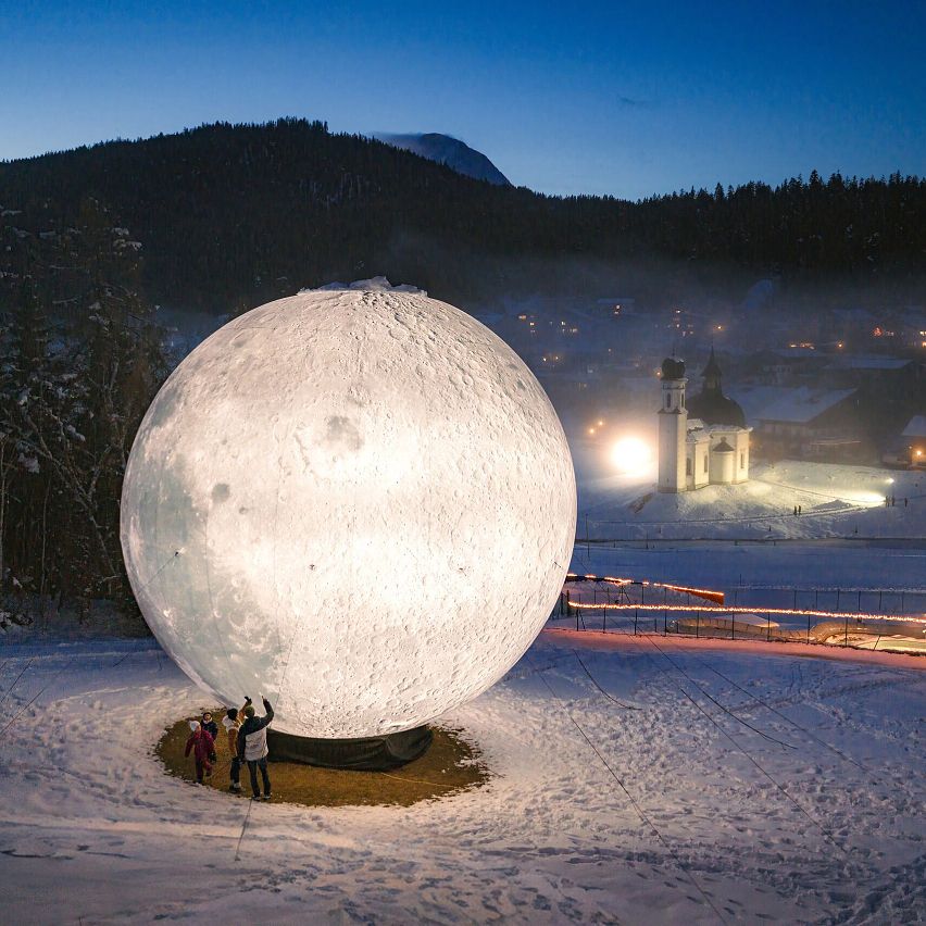 Ein großer beleuchteter Mond in der Region Seefeld, umgeben von Schnee und Bäumen bei Nacht.