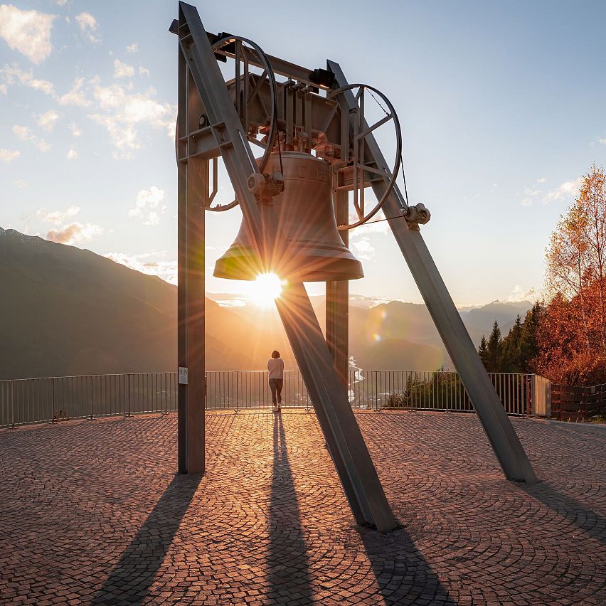 Friedensglocke im Herbst - Frau blickt ins Inntal beim Sonnenuntergang - Sonnenstern an der Glocke