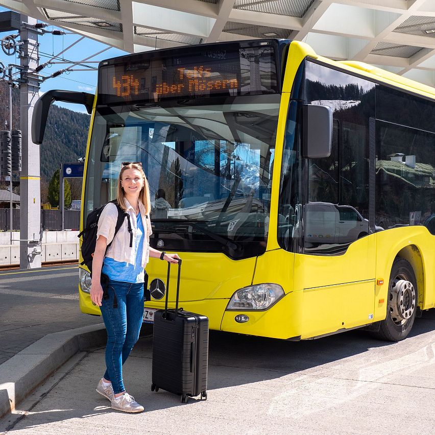 Gast mit Koffer vor einem Bus
