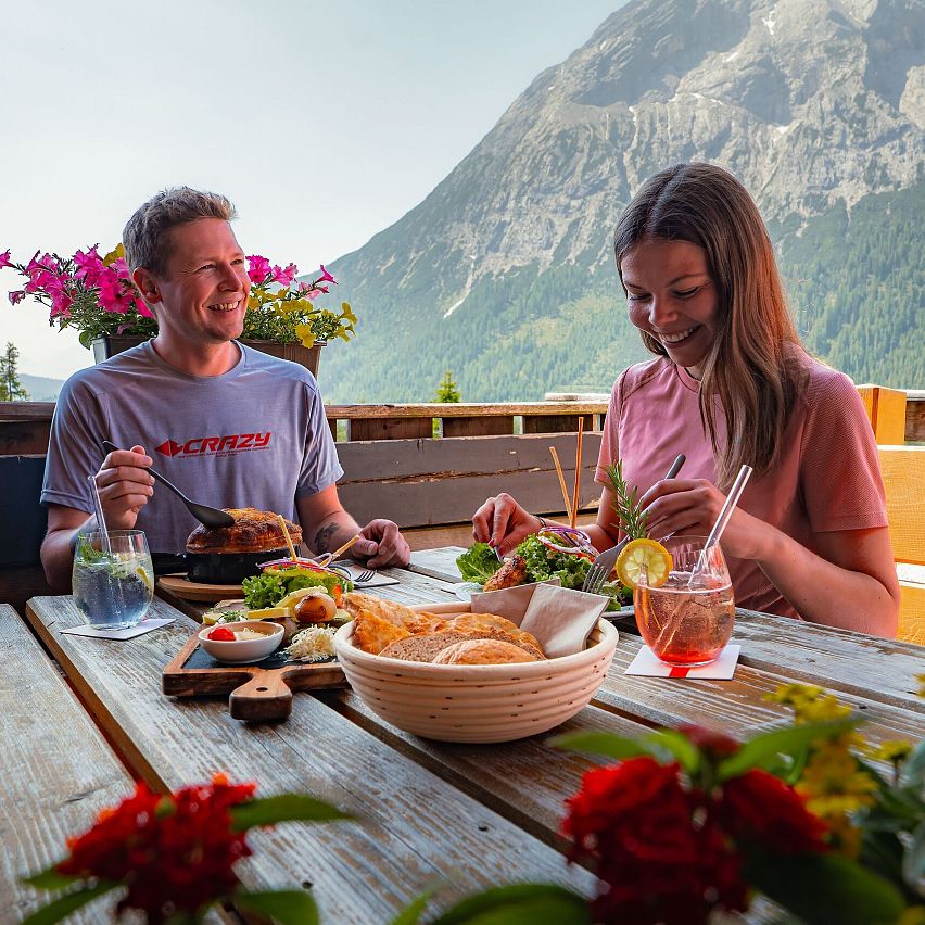 Hämmermoosalm im Sommer_Paar am gedeckten Tisch lacht