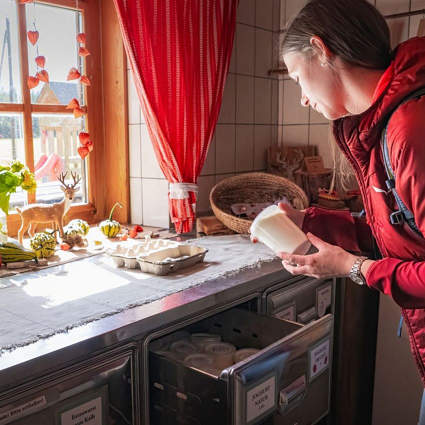 Hofladenrunde Leutasch - Frau schaut sich Joghurt an im Hofladen Thoamlhof