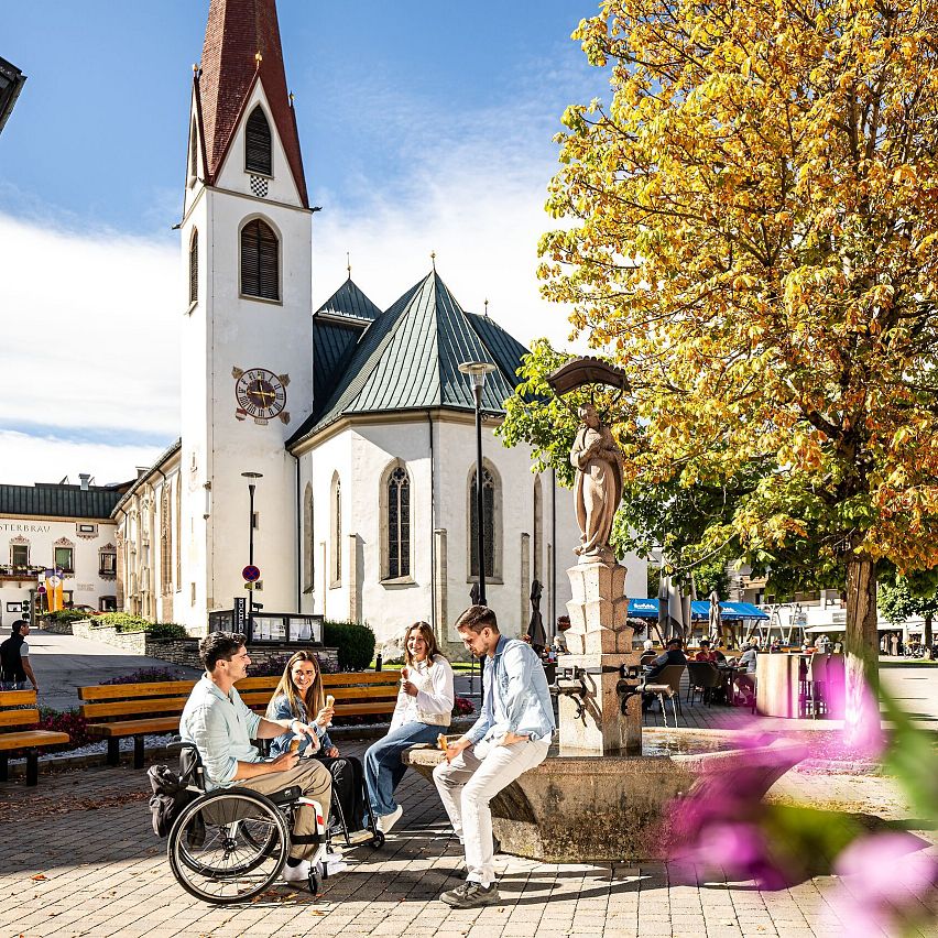 Gruppe junger Leute sitzt bei Kirche im Zentrum der Region Seefeld.