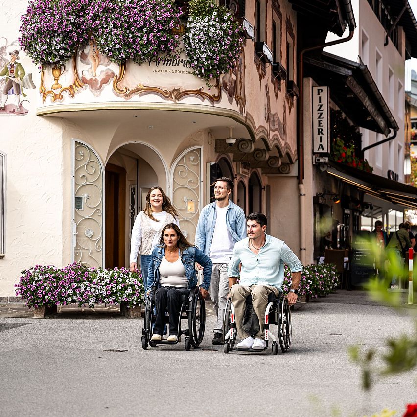 Gruppe mit Rollstühlen in malerischer Straße der Region Seefeld.