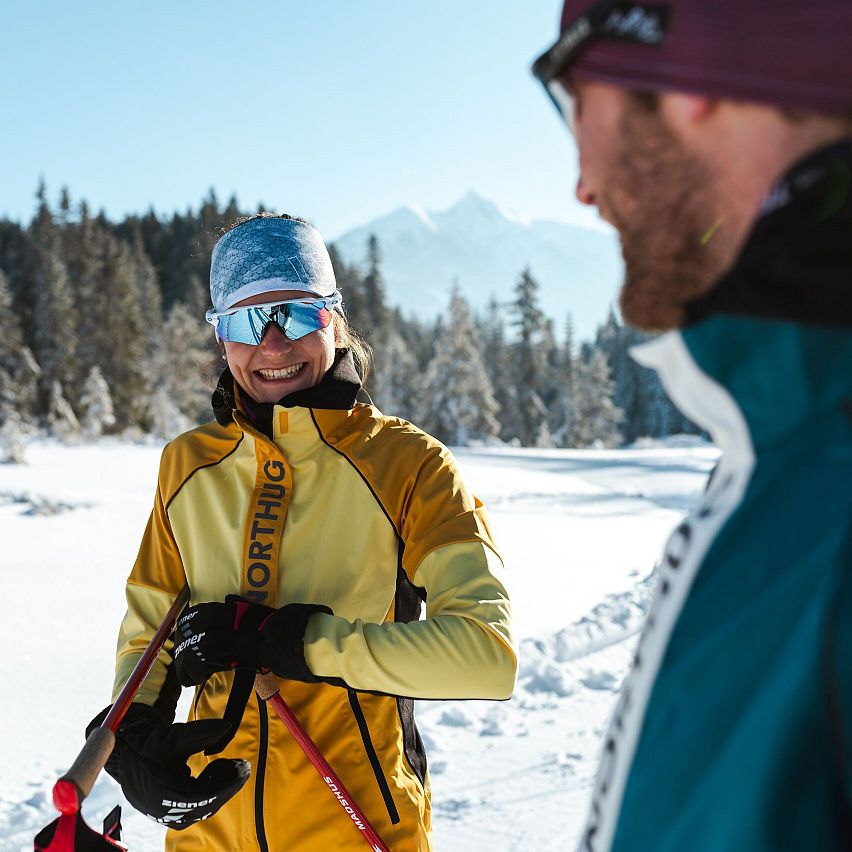 Familie genießt ein Frühstück auf der Terrasse in der Region Seefeld, umgeben von schneebedeckten Bergen und Sonnenschein.
