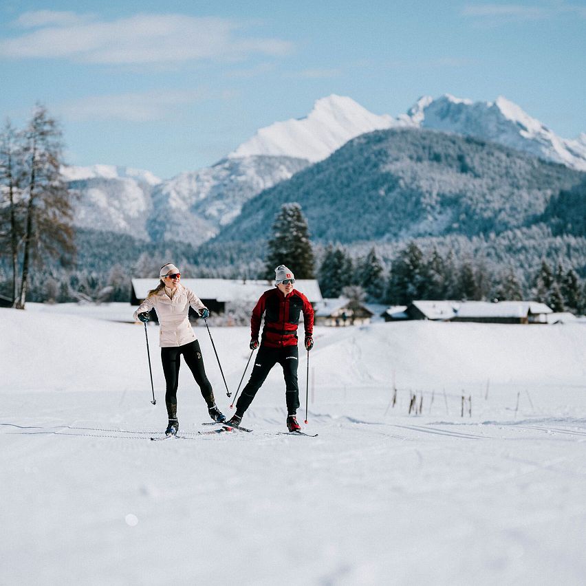 Zwei Langläufer in der Region Seefeld vor schneebedeckten Alpen.