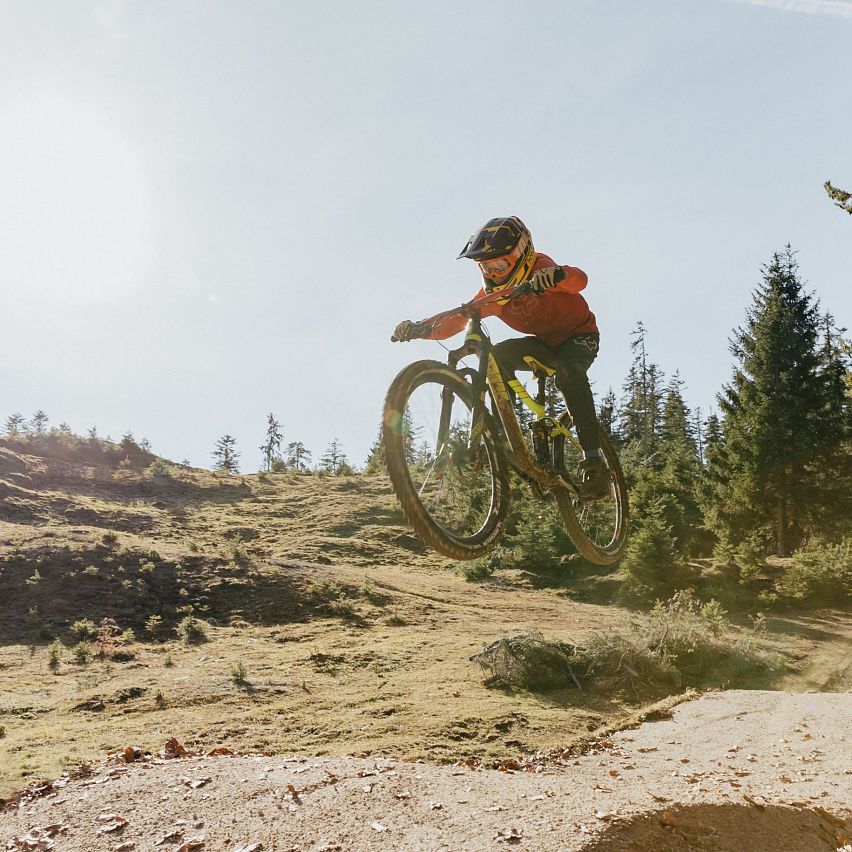 Mountainbiker springt über Hügel in herbstlicher Landschaft in der Region Seefeld.
