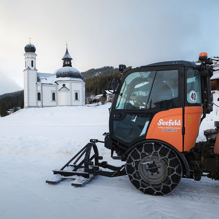 Winterlandschaft in der Region Seefeld mit Kirche und Schneeräumfahrzeug.
