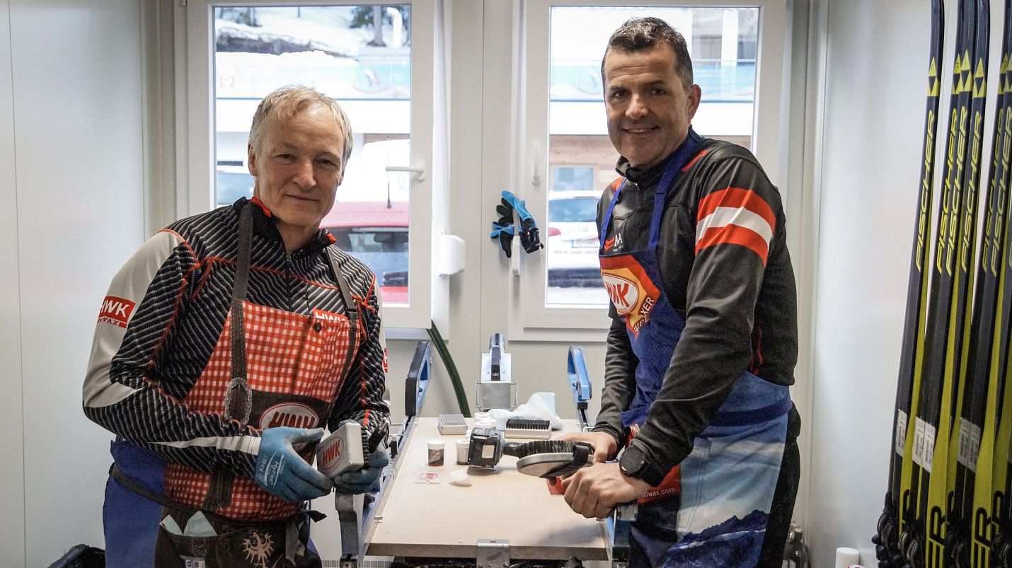Zwei Männer arbeiten an Skiern in einem Skiservice-Raum.