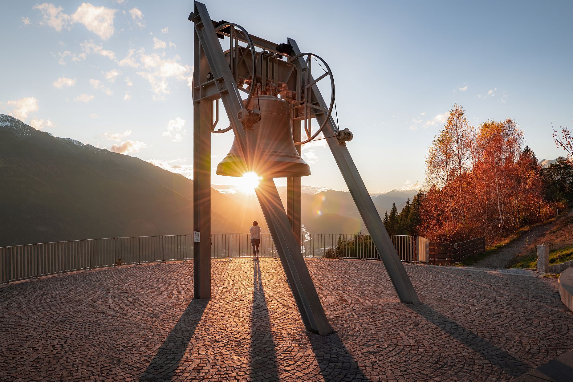 Friedensglocke im Herbst - Frau blickt ins Inntal beim Sonnenuntergang - Sonnenstern an der Glocke
