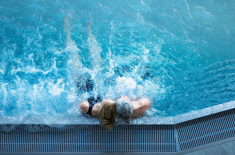 Alpenbad Leutasch im Frühling_Paar im Indoor-Pool lehnt sich aneinander
