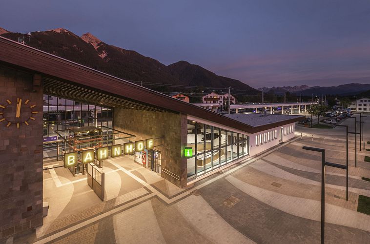 Moderner Bahnhof mit markantem Eingang, umgeben von einer ruhigen Landschaft.