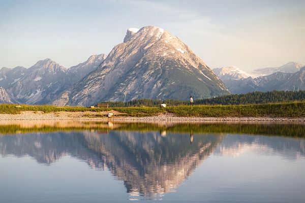 Drohnenaufnahme Gschwandtkopf Speichersee - Person läuft entlang des Speichersees mit Hohe Munde im Hintergrund