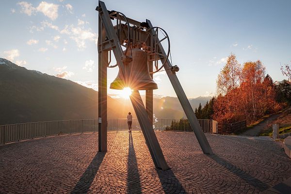 Friedensglocke im Herbst - Frau blickt ins Inntal beim Sonnenuntergang - Sonnenstern an der Glocke