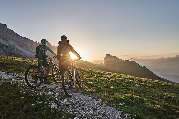 Radfahrer bei Sonnenaufgang in der Region Seefeld, Berge im Hintergrund. Mountainbiken im Morgenlicht.