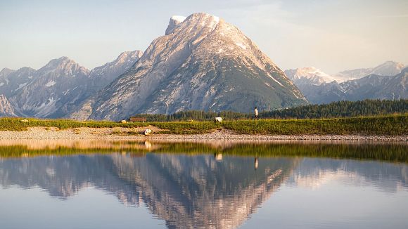 Drohnenaufnahme Gschwandtkopf Speichersee - Person läuft entlang des Speichersees mit Hohe Munde im Hintergrund