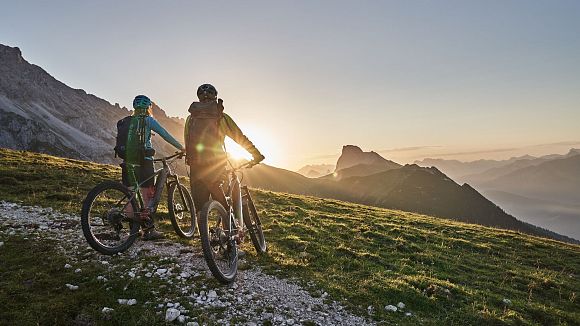 Radfahrer bei Sonnenaufgang in der Region Seefeld, Berge im Hintergrund. Mountainbiken im Morgenlicht.