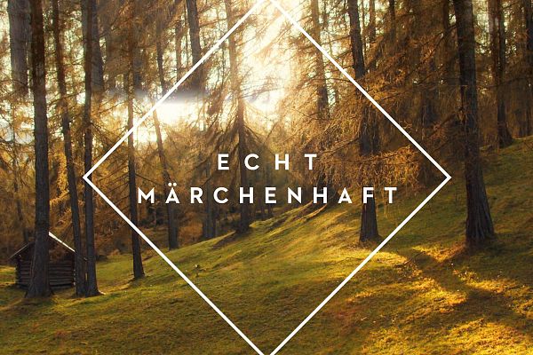 Wald mit Sonnenlicht und Schriftzug 'Echt märchenhaft'. | Forest with sunlight and text 'Truly magical'.