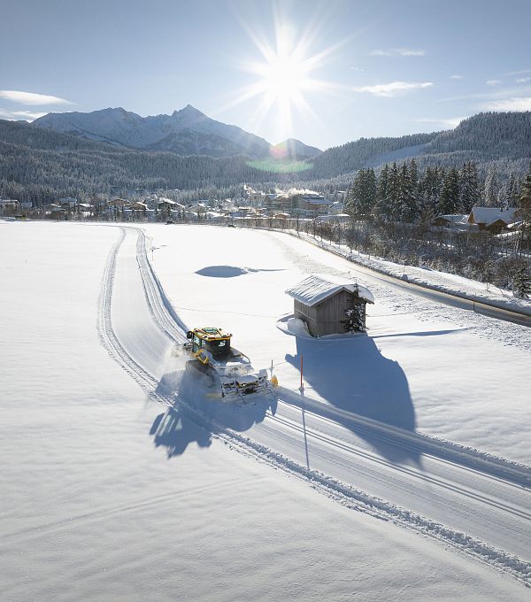 Drohnenaufnahme E-Bulli auf A7 Loipe mit Hütte mit Sonnenstern