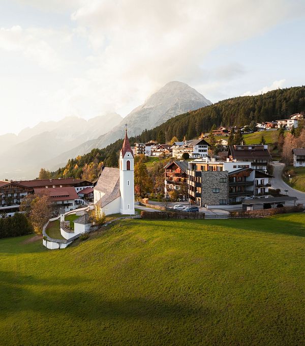 drohnenaufnahme-moesern-im-herbst-kirche-mit-hohe-munde-bei-sonnenuntergangsstimmung-1