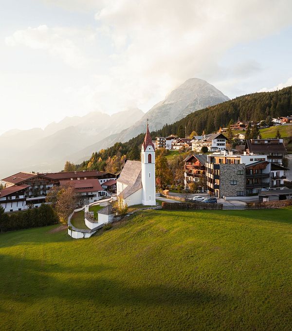 drohnenaufnahme-moesern-im-herbst-kirche-mit-hohe-munde-bei-sonnenuntergangsstimmung-17