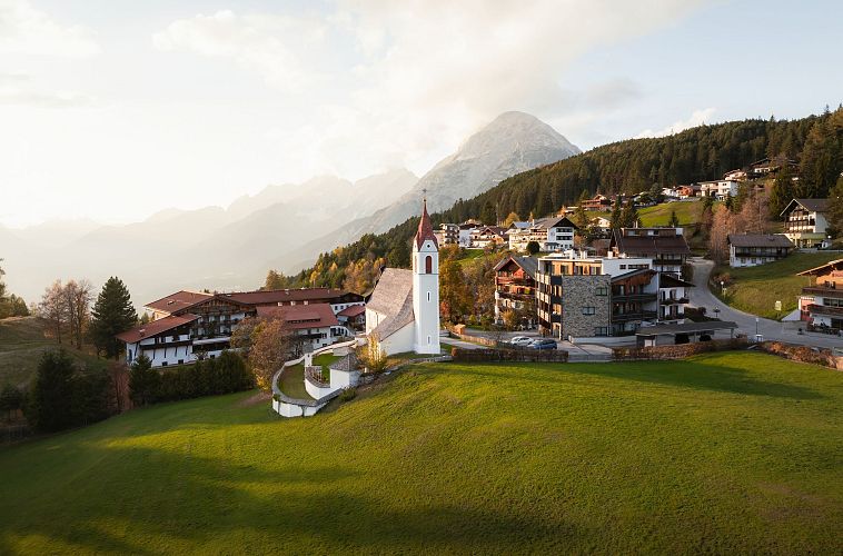 Drohnenaufnahme Mösern im Herbst_Kirche mit Hohe Munde bei Sonnenuntergangsstimmung