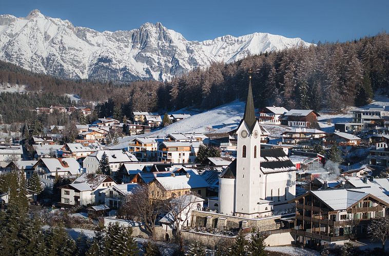 Drohnenaufnahme Reith im Winter - Kirche reingezoomt mit Wettersteingebirge im Hintergrund