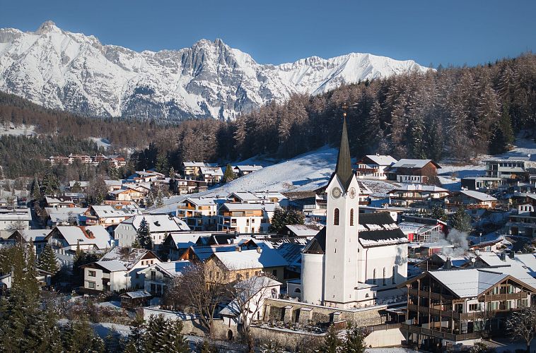 drohnenaufnahme-reith-im-winter-kirche-reingezoomt-mit-wettersteingebirge-im-hintergrund-4