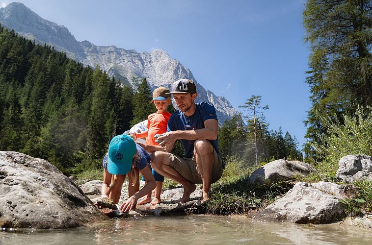 familien-weitwanderung-im-gaistal-familie-an-leutascher-ache-vater-und-tochter-holen-grosse-steine-aus-dem-wasser-tochter-bueckt-sich-4