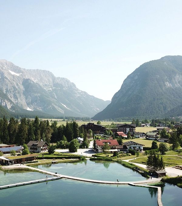 A panoramic view of a valley with a lake and mountains in the background.