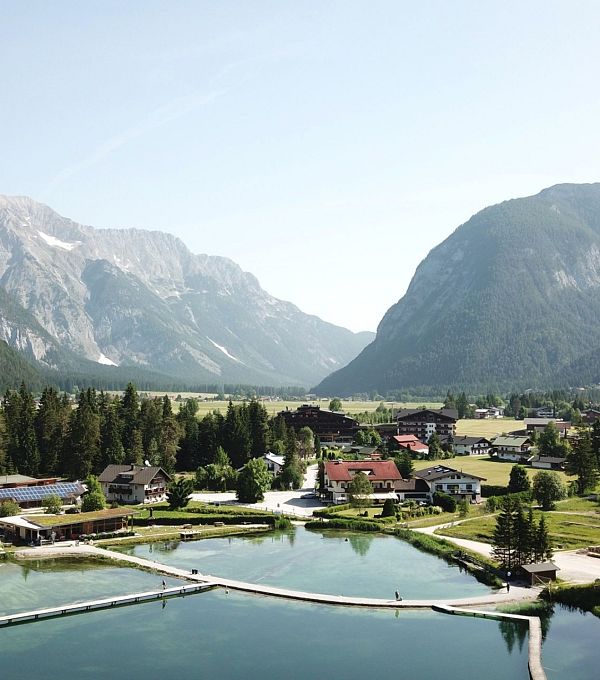Landschaft mit einem klaren See, umgeben von Bergen und Wäldern.