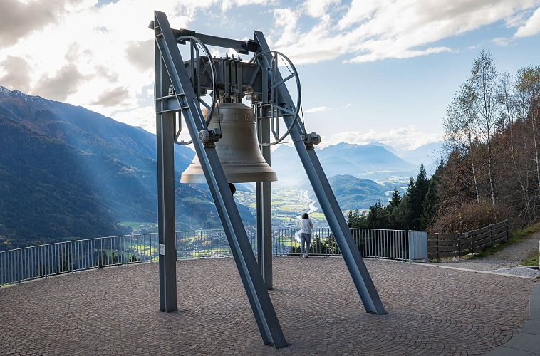 Friedensglocke im Herbst - Frau steht am Geländer und blickt ins Inntal