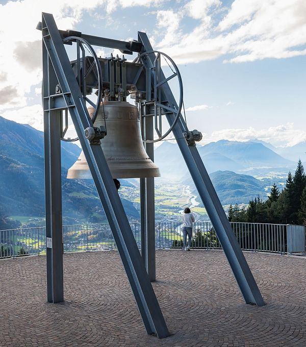 Friedensglocke im Herbst - Frau steht am Geländer und blickt ins Inntal