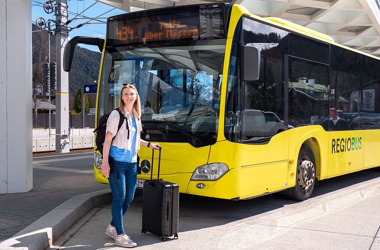 Gast mit Koffer vor einem Bus