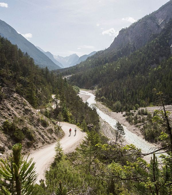 Wanderpfad im grünen Tal der Region Seefeld mit Fluss und Bergen.