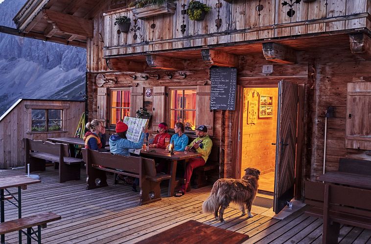 gruppe-auf-der-terrasse-der-rotmoosalm-im-gaistal-am-abend-gemuetlicher-huettenabend-5-1