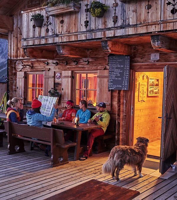 gruppe-auf-der-terrasse-der-rotmoosalm-im-gaistal-am-abend-gemuetlicher-huettenabend-5-2