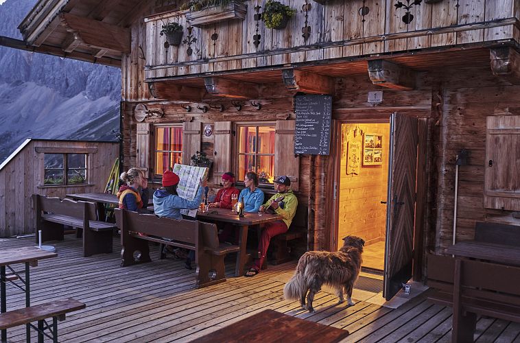 gruppe-auf-der-terrasse-der-rotmoosalm-im-gaistal-am-abend-gemuetlicher-huettenabend-5