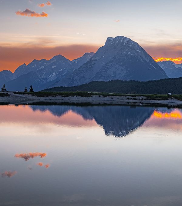 Mountain landscape at sunset with reflection in still water.