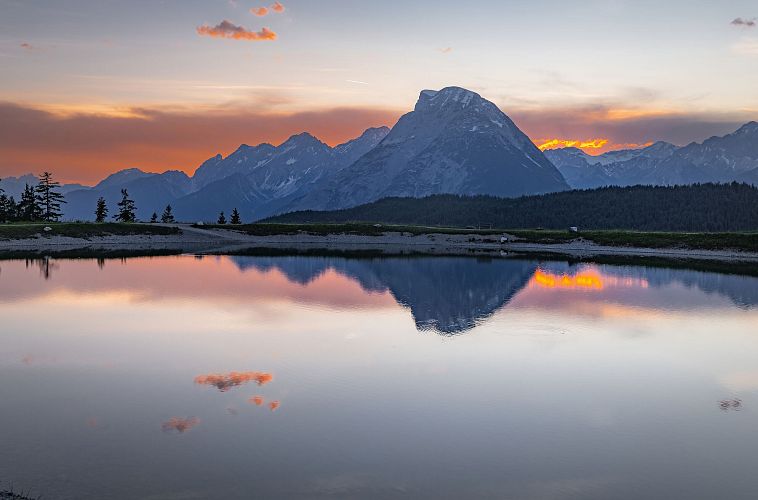 Paesaggio montano al tramonto con riflesso nella piscina.