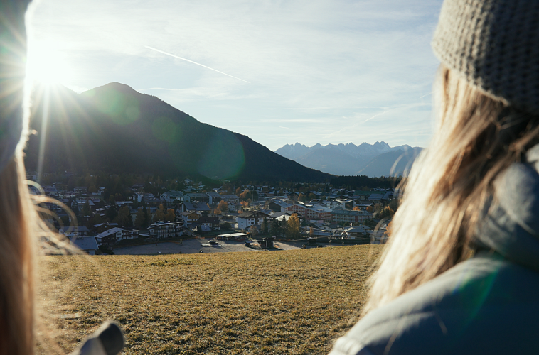 Blick auf die Region Seefeld mit Bergen bei Sonnenuntergang, im Vordergrund zwei Personen von hinten.