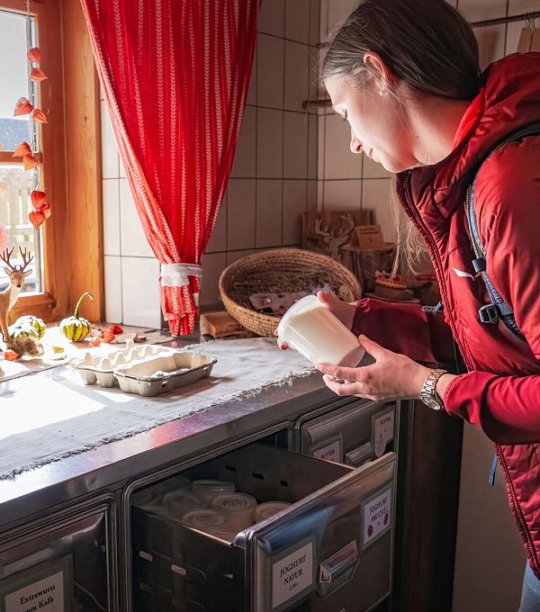 Hofladenrunde Leutasch - Frau schaut sich Joghurt an im Hofladen Thoamlhof