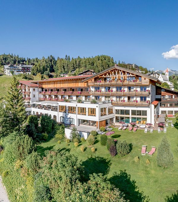 A hotel set in a green landscape, surrounded by trees and hills.