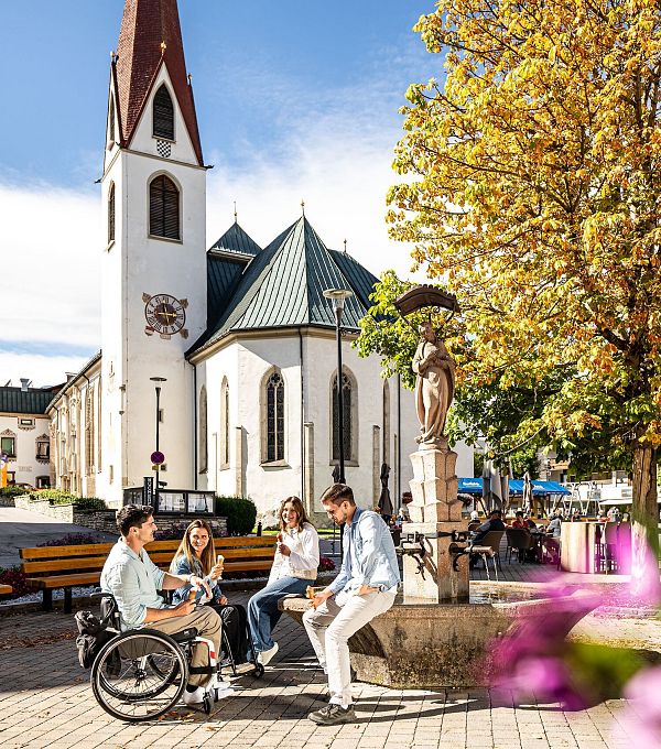 Gruppe junger Leute sitzt bei Kirche im Zentrum der Region Seefeld.