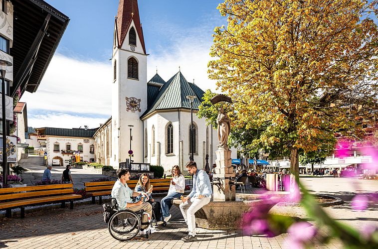 Gruppe junger Leute sitzt bei Kirche im Zentrum der Region Seefeld.