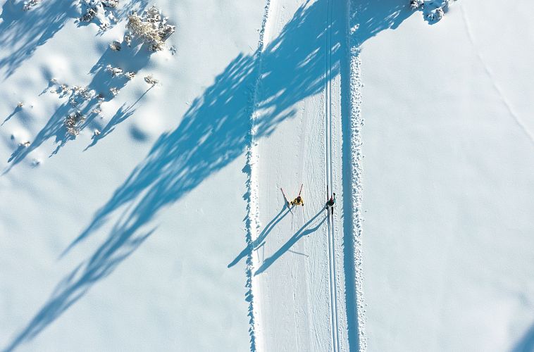 Langläufer in der verschneiten Region Seefeld, klare Spuren auf dem Schnee, lange Schatten im Sonnenlicht, Winterlandschaft.