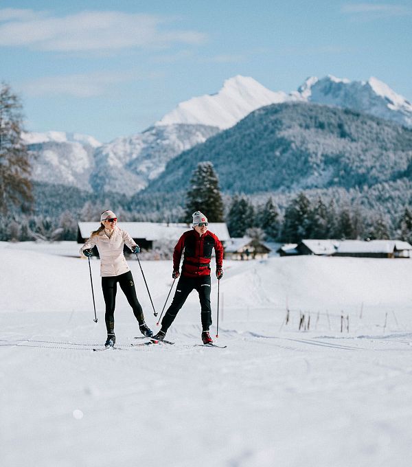 Zwei Langläufer in der Region Seefeld vor schneebedeckten Alpen.