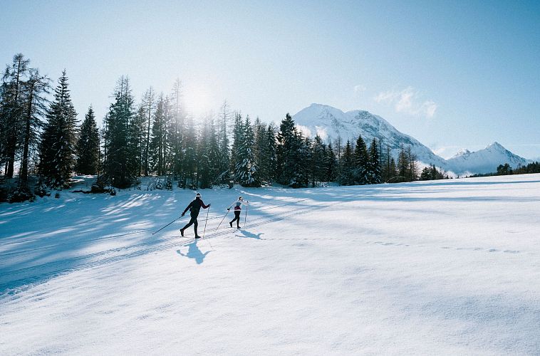 Langlaufen in der Region Seefeld_zwei Langläufer auf C9 Plaik Loipe in Leutasch_Weitwinkelaufnahme gegen die Sonne