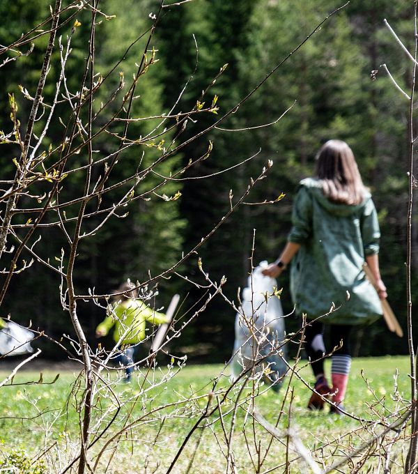 A group of people is playing outside in a green area, seen through branches.