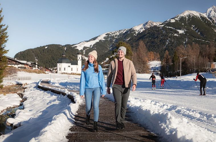 Mann und Frau laufen neben Loipe in Seefeld
