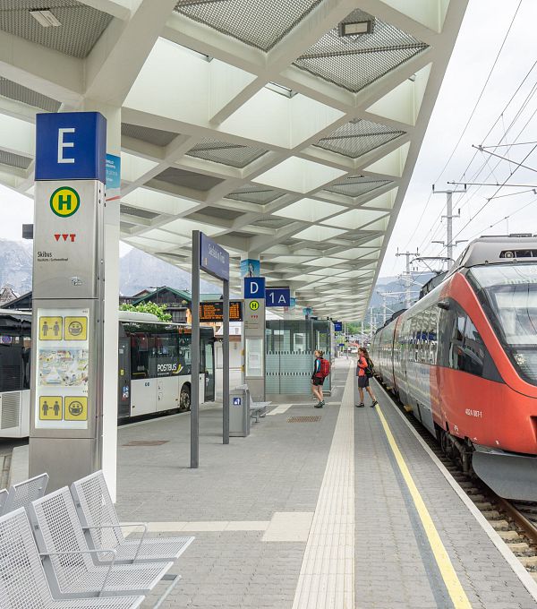 Ein Zug der ÖBB am Bahnsteig, neben einem wartenden Bus.